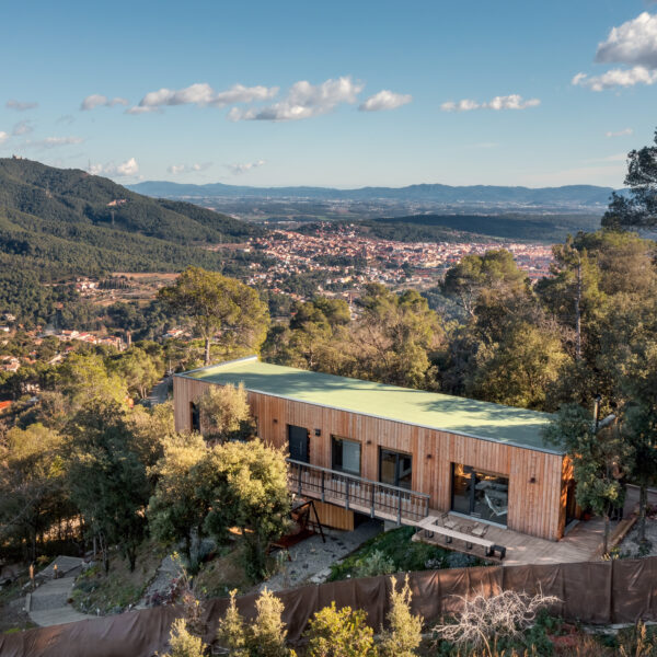 Vista aèria d'una casa passiva Eskimohaus. Es tracta d'una casa d'una planta, allargada en mig d'un entorn boscos mediterrani.